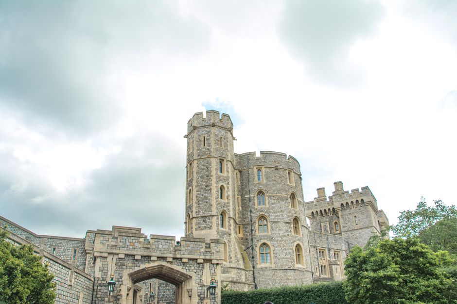 Exterior view of a historic stone building with multiple narrow, arched windows and a crenellated parapet at the top, typical of castle or fortress architecture. The facade is constructed from large, 